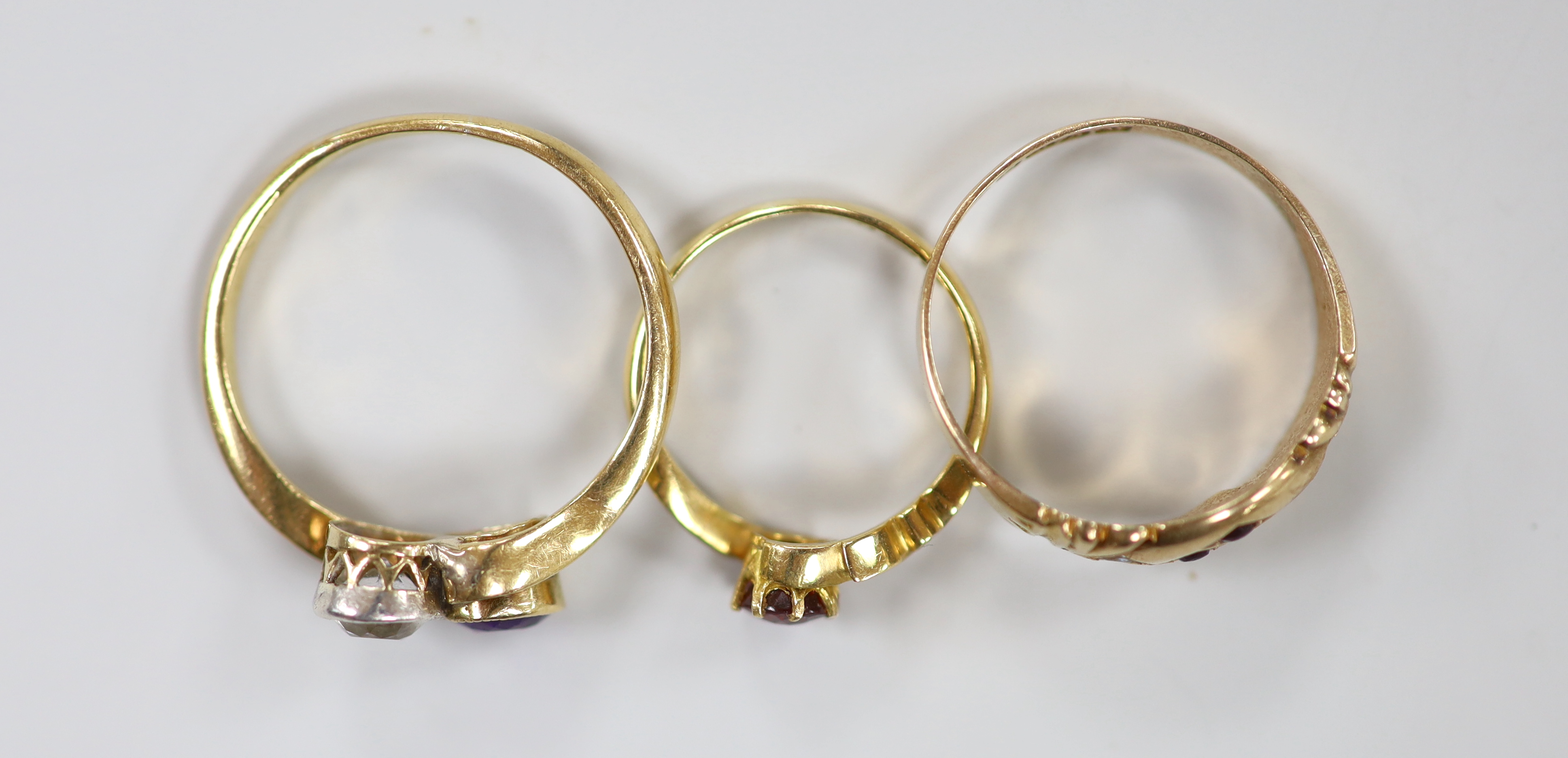 An 18ct, amethyst and simulated diamond set crossover ring, an 18ct and red stone ring, gross weight 4.7 grams and a late Victorian 9ct ring, gross 1.6 grams.